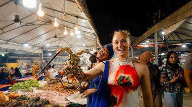 Traveller holding an ornate spiny lobster at a market in Malaysia