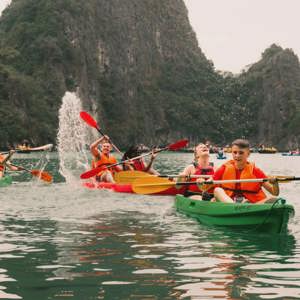 Young travellers kayaking between towering limestone karsts in Ha Long Bay Vietnam - Contiki Best of Vietnam Tour