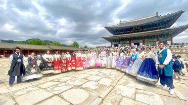 Travellers stood in traditional hanbok dress outside of the Gyeongbokgung Palace, Seoul, South Korea
