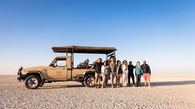 Travellers posing in front of safari truck on the Makgadikgadi Salt Pans in Botswana, Africa