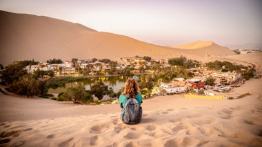Traveller sitting on the dunes overlooking Huacachina, Peru