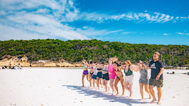 Travellers walking across beach together, Whitsunday Islands, Australia