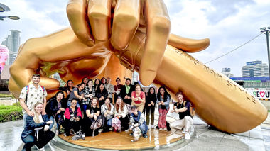 Group of travellers sat and stood under the Gangnam style dance arms, Seoul-Hongdae, South Korea
