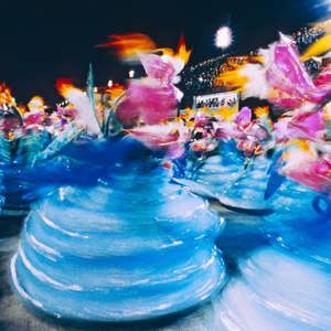 Motion-blurred samba dancers in vibrant blue and pink carnival costumes at the Sambadrome Rio Carnival Brazil - Contiki Brazil Tour
