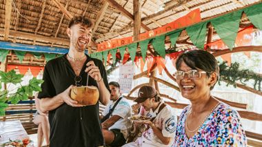 Traveller Laughing with Local and Enjoying Drink from a Coconut, Port Barton, Philippines