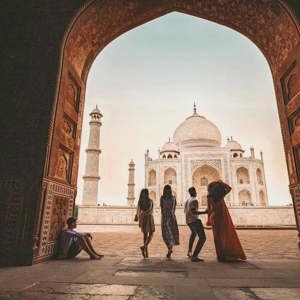 Travellers framed through the ornate Great Gate archway looking towards the Taj Mahal white marble mausoleum in Agra India - Contiki Eternal India Tour