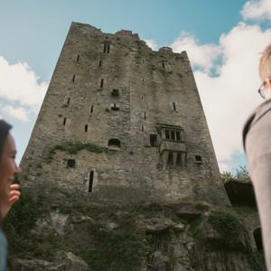 Two people look up at the historic Blarney Castle in County Cork - Contiki Ireland in a Week Tour
