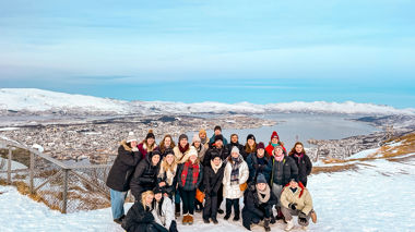 A group of travellers posing for a photo at a scenic viewpoint of Tromso, Norway