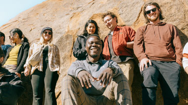 Travellers smiling at the camera standing and sitting on a rock