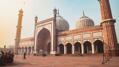 Red sandstone mosque with white marble domes and tall minarets, Delhi, India.