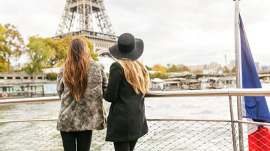 Two travellers looking out across Paris from the boat on the River Seine cruise in Paris, France
