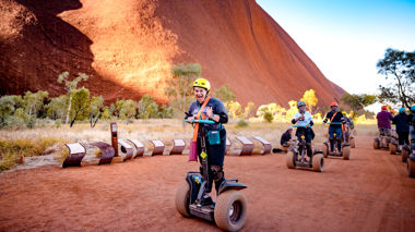 Travellers on a segway next to Uluru, Australia