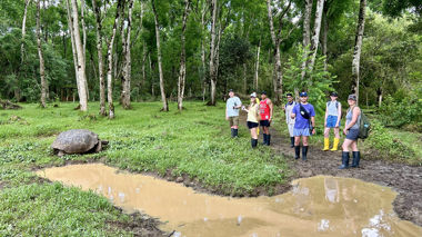 Travellers standing near a tortoise on Isabela Island, Ecuador