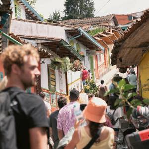 Travellers exploring the vibrant colourful colonial streets of Guatapé in Antioquia Colombia lined with painted buildings and artisan market stalls - Contiki Best of Colombia Tour