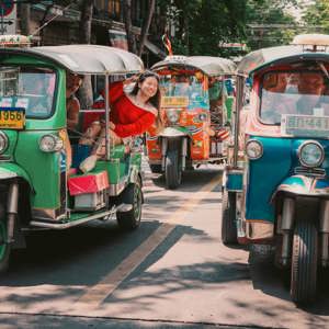 Travellers ride colourful tuk-tuks through the streets of Bangkok on the Contiki Best of Thailand Tour