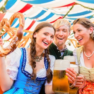 Travellers in traditional dress enjoying pretzels and steins at Oktoberfest in Beer Tent in Munich, Germany