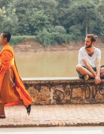 A Buddhist walking along the Nam Khan River in Luang Prabang, Laos