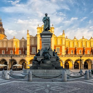 Statue in large square with historic building and arches behind in Krakow, Poland