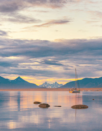 A landscape view of a colourful sunset over a lake with a boat in Puerto Natales, Patagonia