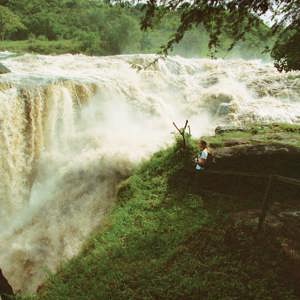 Traveller standing at the viewing platform beside the thundering Murchison Falls on the Victoria Nile in Murchison Falls National Park Uganda - Contiki Uganda Tour