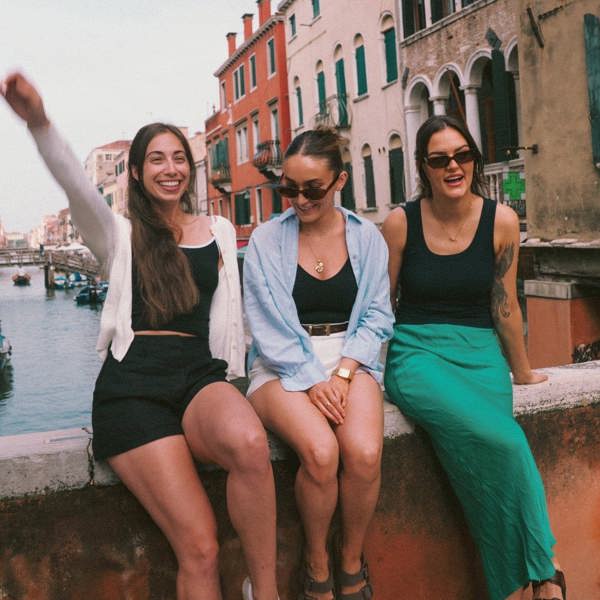 Contiki travellers relaxing on a bridge overlooking a canal in Venice, Italy, on the Vienna to Rome Trail Tour