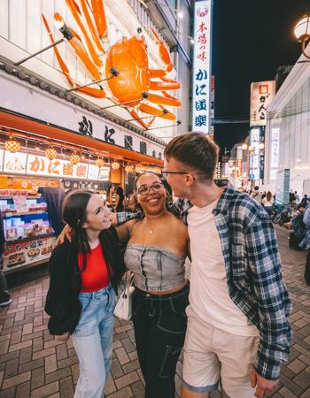 Three Travellers with Arms Around Each Other in Street of Osaka, Japan