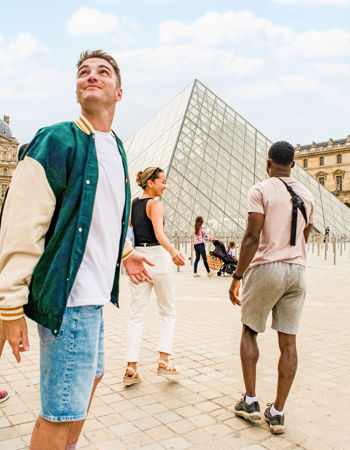Four travellers exploring Paris together, outside the Louvre in France