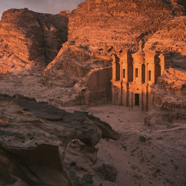 The Monastery in Petra glows at sunset, surrounded by towering sandstone cliffs on the Contiki Best of Egypt & Jordan Tour