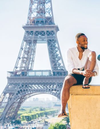 Travellers sitting in front of the Eiffel Tower in Paris, France