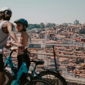 Two people cycling above Porto with panoramic views of the historic city and Douro River on Contiki's Lisbon to Barcelona Tour