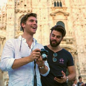 Two Contiki travellers reviewing photos in front of Milan Cathedral (Duomo di Milano), capturing memories while exploring Milan on the Tuscany, Milan & Venice 35 to 45 Tour