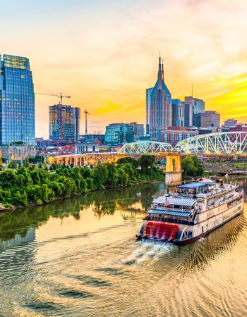 Boat Cruising the Cumberland River at Night against Skyline of Nashville, USA