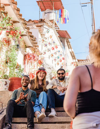 Three travellers sitting on steps surrounded by decorations and flowers in Cusco,Peru