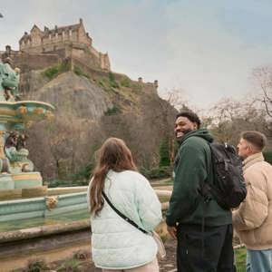 Travellers explore Princes Street Gardens with Edinburgh Castle in the background on the Contiki Best of England & Scotland Winter Tour