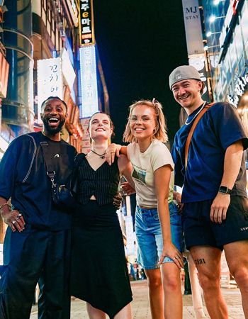 Travellers Stood Smiling in Colourful Lit Up Street in Seoul, South Korea