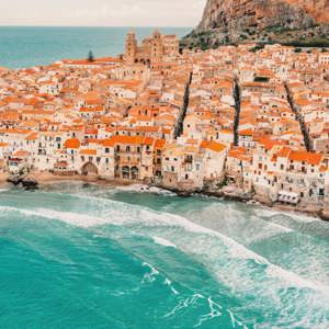 Aerial view of Cefalù's historic coastline and sandy beach in Sicily on the Contiki Best of Italy with Sicily Tour