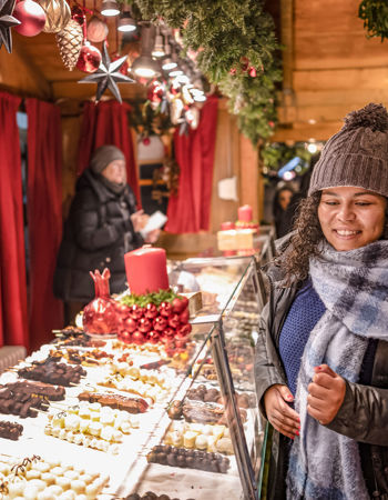 Travellers buying sweet treats from a chocolate stand in a Christmas Market in Frankfurt, Germany