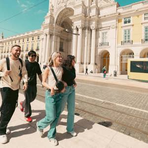 Contiki travellers exploring Lisbon’s Praça do Comércio beside the iconic yellow tram, discovering historic landmarks on the Spain & Portugal Panorama Tour