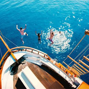 Travellers jump from a sailing boat into the crystal-clear Aegean Sea on Contiki's Greek Island Hopping 35 to 45 Tour