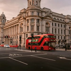 A classic red double-decker bus travels through central London at sunset on the Contiki London Mini Break