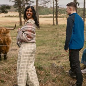 A group meeting a Highland cow in the Scottish Highlands - Contiki Scotland in a Week tour