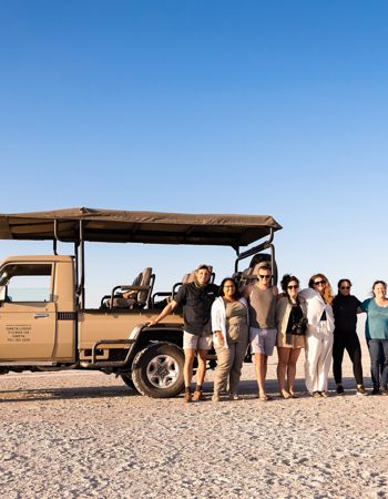 Travellers posing in front of safari truck on the Makgadikgadi Salt Pans in Botswana, Africa