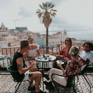 A group relaxing at a terrace café overlooking Lisbon on Contiki's Best of Portugal Tour