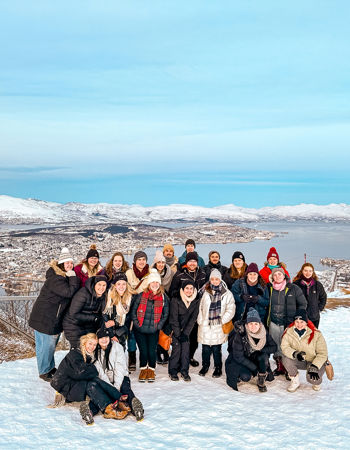 A group of travellers posing for a photo at a scenic viewpoint of Tromso, Norway