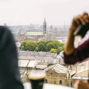 Traveller drinking a pint of Guinness at the Guinness Storehouse rooftop bar overlooking the Dublin city skyline - Contiki St Patrick's Day Festival Tour Ireland