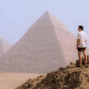 A Contiki traveller stands in the desert overlooking the Pyramids of Giza, taking in one of Egypt's most iconic ancient landmarks - Egypt Explorer Tour