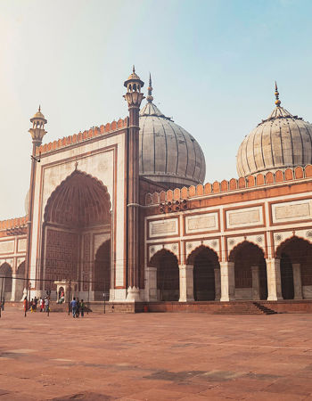 Red sandstone mosque with white marble domes and tall minarets, Delhi, India.