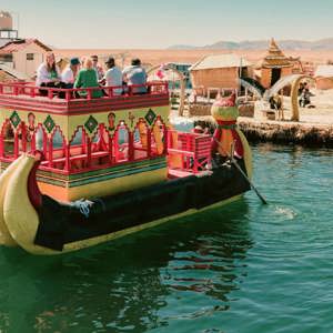 Contiki travellers cruising on a traditional reed boat at the Uros Floating Islands on Lake Titicaca, experiencing local culture on the Peru Uncovered Tour